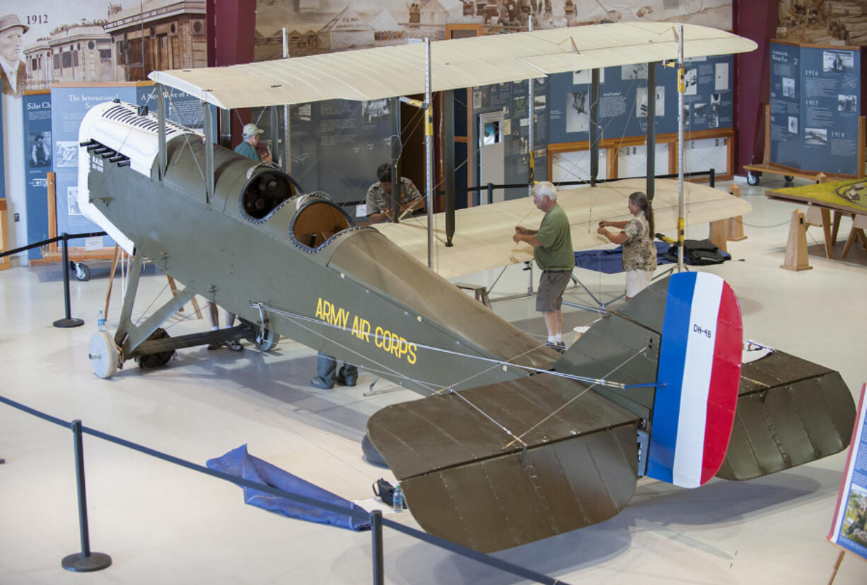 Acting chief ranger Bob Cromwell, left, on the other side of the wing, and Century Aviation restorers Mark Smith and Karen Barrow prepare a DeHavilland DH4-B biplane for this morning&#039;s unveiling at Pearson Air Museum.