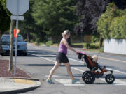 Rebekah Latham crosses Southeast Park Crest Avenue with her baby, Scarlett, 1, after using a curb cut, which was built on the street thanks to a grant to make the street safer and more pedestrian friendly. The Cascade Highland Neighborhood Association also received grants to plant trees, add street lights and stripe crosswalks.