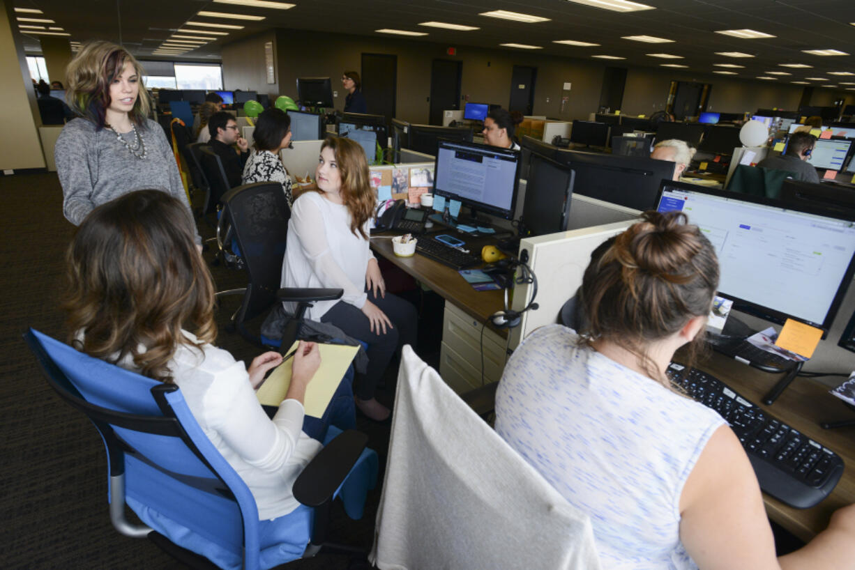 Michelle Hampton, manager of project research at DiscoverOrg in Vancouver, left, chats with employee Savannah King, center, and other team members at DiscoverOrg, which announced it will hire 200 new employees in the next year after more than doubling its staff in 2015.