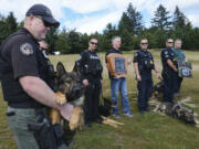 Clark County sheriff&#039;s Deputy Seth Brannan, left, holds his dog, Ringo, Monday at the newly named Ike Memorial Dog Park during a ceremony dedicating the park to Ike. Ike, a K-9 with the Vancouver Police Department, died in the line of duty last year. Jack Anderson, Ike&#039;s handler, stands at center with a park dedication plaque.