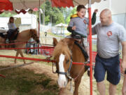 Eleven-year-old Cavan Franklin, who has cerebral palsy, rides a pony Monday at the Clark County Fair with the help of Scott Taube, a captain at Clark County Fire District 6, and Cavan&#039;s mom, Brandi Franklin. Cavan was one of six children chosen to participate in the local Memory Makers program, which guides medically fragile children and their families through the fair.