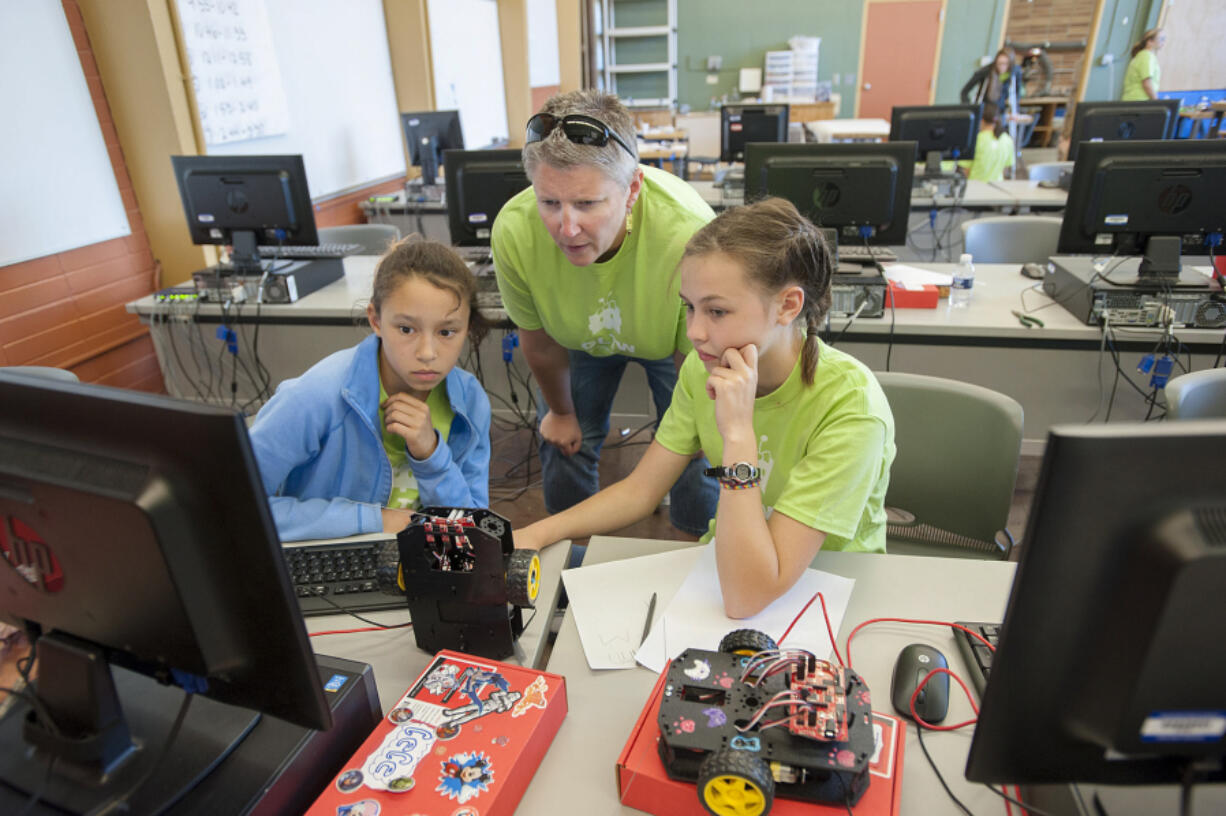 Cecelia Fox-Middleton, 12, from left, joins camp director Cyndy Hagin and fellow camper Amelia Martin, 12, as they write code for their robot. The goal of the Girls Lead The Way summer robotics camp is to expose girls to technical careers.