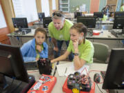 Cecelia Fox-Middleton, 12, from left, joins camp director Cyndy Hagin and fellow camper Amelia Martin, 12, as they write code for their robot. The goal of the Girls Lead The Way summer robotics camp is to expose girls to technical careers.