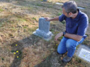 Ed Senchyna, senior grounds maintenance worker at the historic Camas Cemetery, crouches by a headstone. Senchyna is the only employee maintaining the cemetery. A former Camas woman recently criticized the city for allowing weeds and grass to overtake some of the headstones.