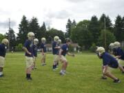 Seton Catholic High School offensive line coach Kasey Powers, center, puts players through a drill during football practice at Cascade Middel School on Thursday May 31, 2012.