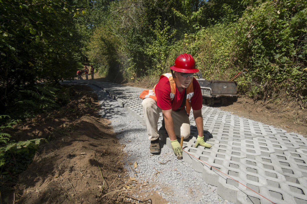 Brock Pluard, a member of a Department of Natural Resources fire crew, lays paving stones along a steep portion of the Ellen Davis Trail in Vancouver on Wednesday afternoon.