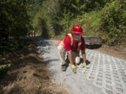 Brock Pluard, a member of a Department of Natural Resources fire crew, lays paving stones along a steep portion of the Ellen Davis Trail in Vancouver on Wednesday afternoon.