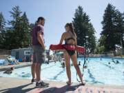 Seth Albert, 21, manager at Camas Municipal Pool, chats with lifeguard Laura Teames while keeping an eye on a busy pool.