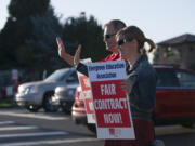 Cascade Middle School teacher Matt Mandrones, left, and his wife, Shawn Mandrones, a teacher at Hockinson Heights Elementary School, wave to drivers Friday morning, Aug. 19, 2016 in Southeast Vancouver.