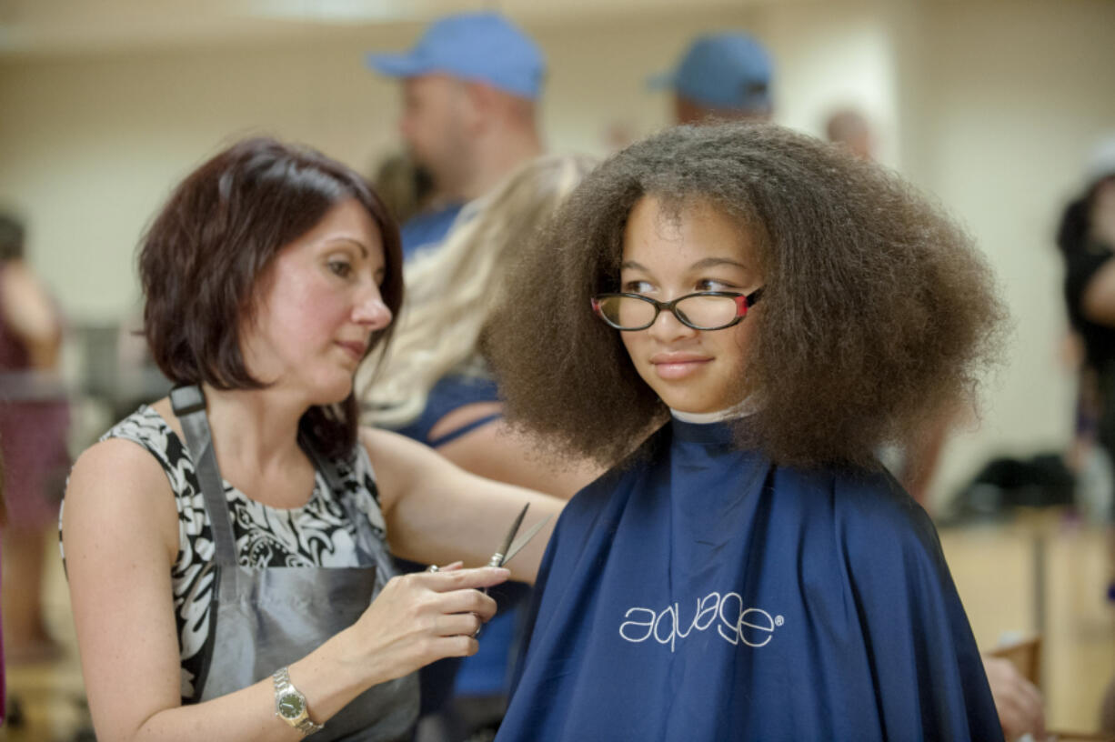 Lisa Houser, left, owner of Utopia Salon, cuts the hair of Arieanna Howard, 11, at the Go Ready back-to-school event Friday at Hudson&#039;s Bay High School. Arieanna will be in 6th grade at Discovery Middle School.