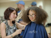Lisa Houser, left, owner of Utopia Salon, cuts the hair of Arieanna Howard, 11, at the Go Ready back-to-school event Friday at Hudson&#039;s Bay High School. Arieanna will be in 6th grade at Discovery Middle School.