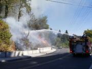 Firefighters douse a brush fire along Northeast Hazel Dell Avenue Wednesday afternoon.