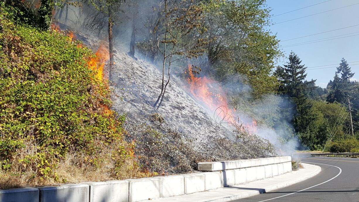 A brush fire burns along Northeast Hazel Dell Avenue, near the 5600 block, Wednesday afternoon.