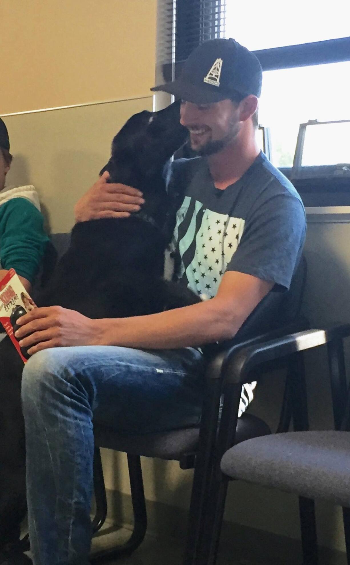 Battle Ground's William Jones greets his black Lab, Hunter, Tuesday, weeks after the dog had run away then was mistakenly adopted out to another family while Jones was away for work.