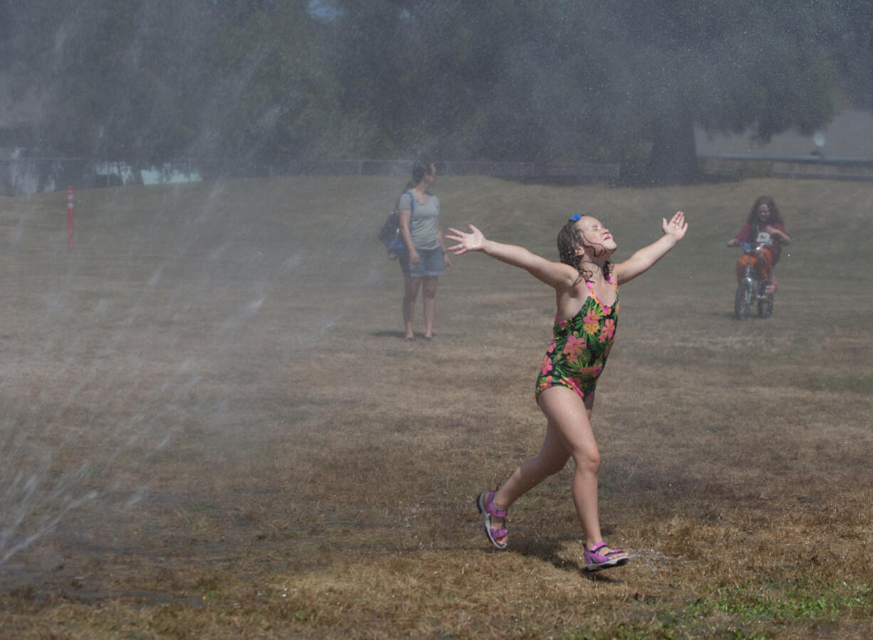 Madison Reaves, 6, of Washougal plays one of her favorite games, &quot;dancing in the rain,&quot; while beating the heat at Hamllik Park in Washougal on Thursday.