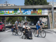 Ian Mackay, of Port Angeles, foreground, is flanked by crew members Josh Blaustein, left, and Adam Mackay, who is also his brother, as they make their way through Vancouver during the final leg of his journey from Anacortes to Portland on his wheelchair.