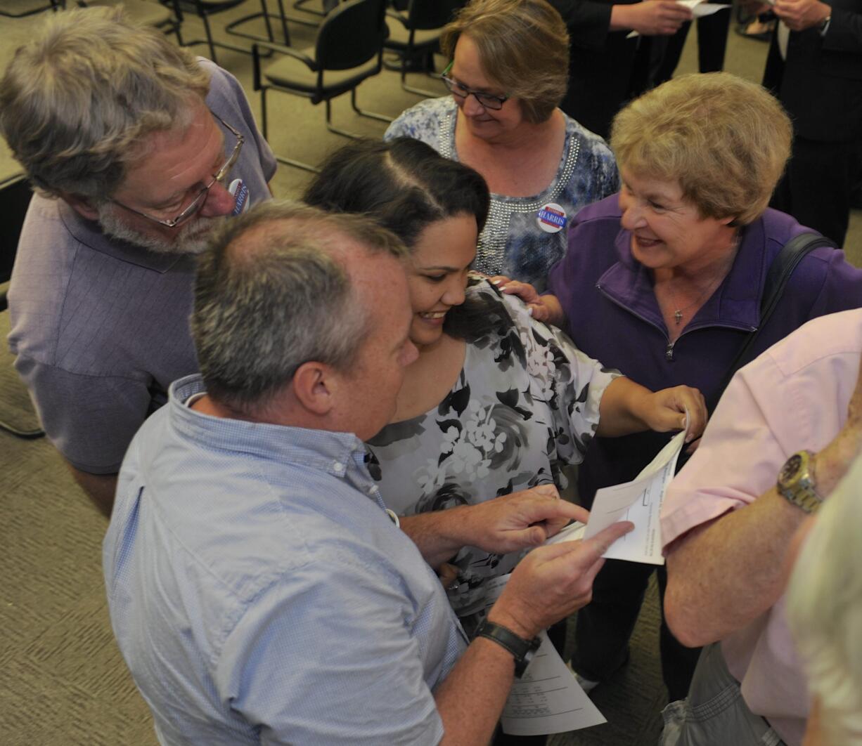 Council candidate Tanisha Harris, center, checks the election results as she is congratulated by her campaign manager Steve Kuyatt, bottom left, and her aunt Dian Stack and her mother Karen Harris, top center, at the Clark County Public Service building in Vancouver,  Tuesday.