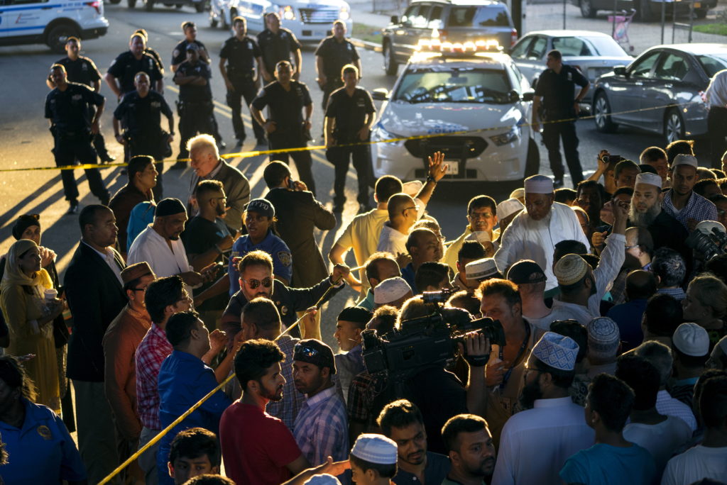 People gather for a demonstration Saturday, Aug. 13, 2016, near a crime scene after an imam and his friend were fatally shot while walking home from a mosque. Police said 55-year-old Imam Maulama Akonjee and his 64-year-old associate, Tharam Uddin, were shot in the back of the head as they left the Al-Furqan Jame Masjid mosque in the Ozone Park section of Queens.