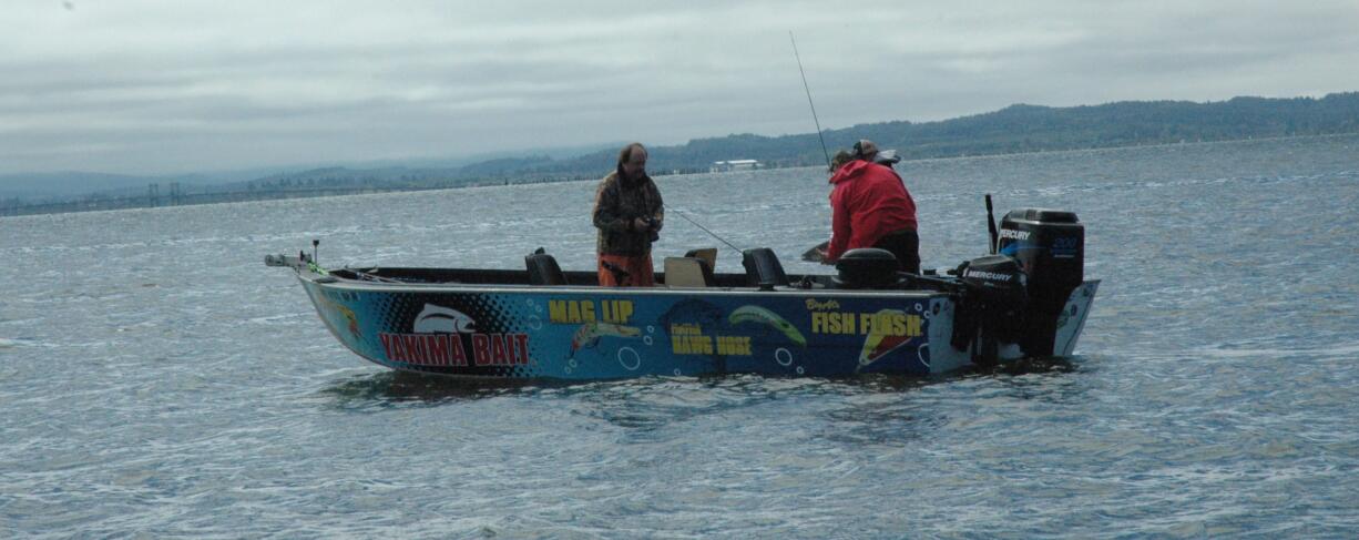 Buzz Ramsey of Klickitat, Wash., takes a photo of Owin Hayes and Dave Calhoun holding a salmon in the Buoy 10 fishery on Monday.