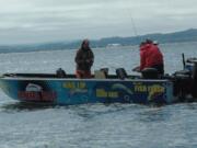 Buzz Ramsey of Klickitat, Wash., takes a photo of Owin Hayes and Dave Calhoun holding a salmon in the Buoy 10 fishery on Monday.