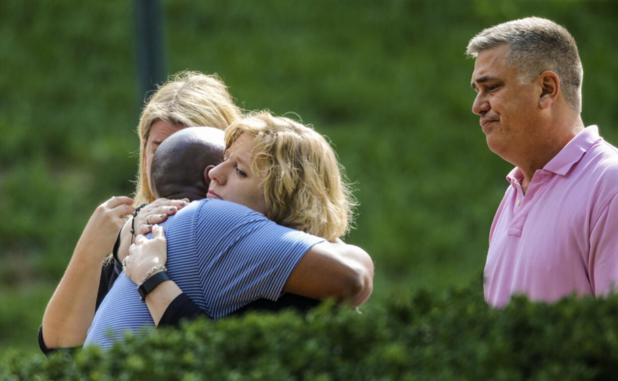 People hug near a crime scene, Tuesday in Roswell, Ga. Detectives on Tuesday were combing through video from multiple cameras and hoping to hear from any possible witnesses near a suburban Atlanta grocery store in the pre-dawn hours before a teenage boy and girl were both found slain, authorities said. The bodies of Natalie Henderson and Carter Davis, both 17, were discovered by a delivery driver behind the Publix supermarket shortly before 6 a.m. Monday, Roswell police said.