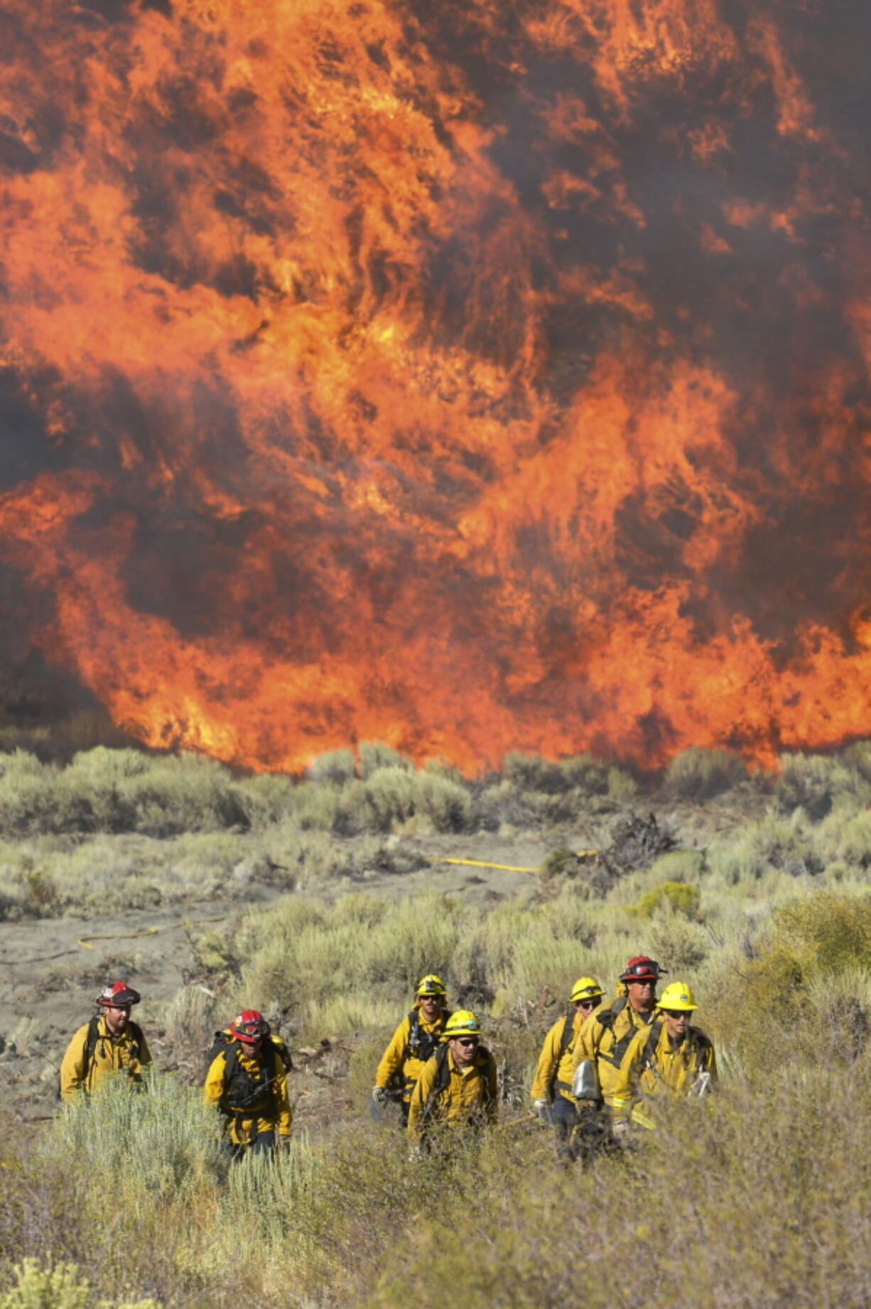 Firefighters scramble from flames after a wildfire blew up near Zermatt Drive and Pacific Crest in Wrightwood, Calif. As flames overtook the pine forests surrounding Wrightwood, only half of the residents in this picturesque mountain town heeded the evacuation orders. Californians are increasingly ignoring the orders, growing accustomed to wildfires as the region faces what could be the most hazardous season yet.