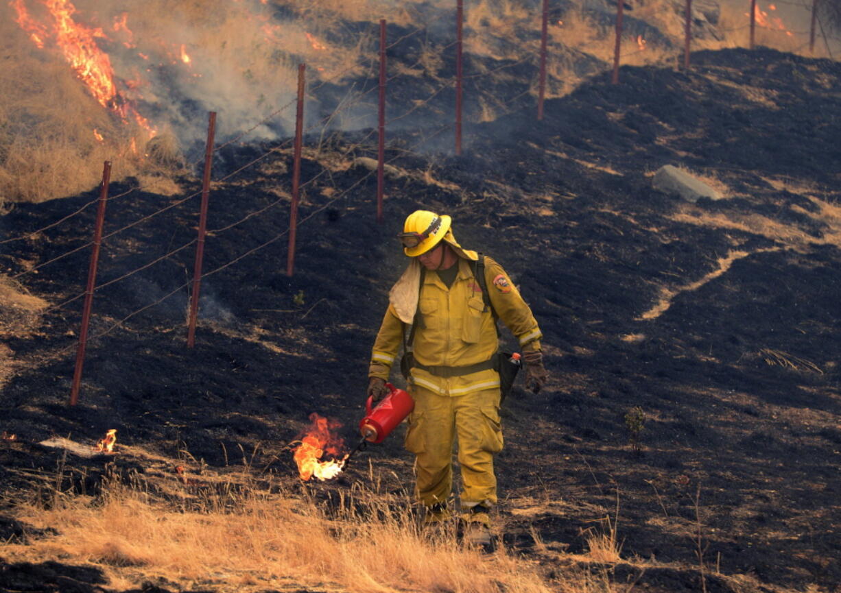 A firefighter lights grass on fire as firefighters perform a firing operation along Interlake Road while battling the Chimney Fire in Southern Monterey County on Aug. 23. The fire started south of Nacimiento Reservoir in San Luis Obispo County.