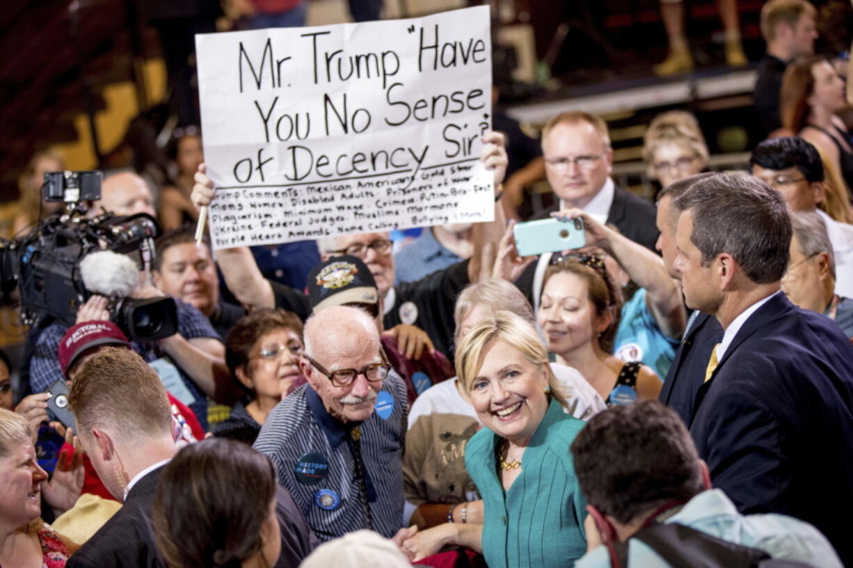 A man holds a sign that reads &quot;Mr. Trump Have You No Sense of Decency Sir&quot; as Democratic presidential candidate Hillary Clinton takes a photograph with a member of the audience after speaking at a rally at Abraham Lincoln High School, in Des Moines, Iowa, on Wednesday.