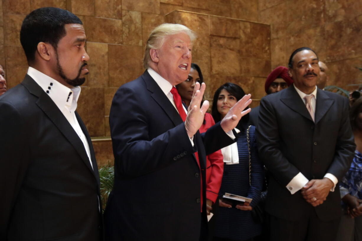 Pastor Darrell Scott listens at left as Republican presidential candidate Donald Trump speaks in Trump Tower building in New York.