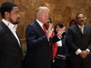 Pastor Darrell Scott listens at left as Republican presidential candidate Donald Trump speaks in Trump Tower building in New York.