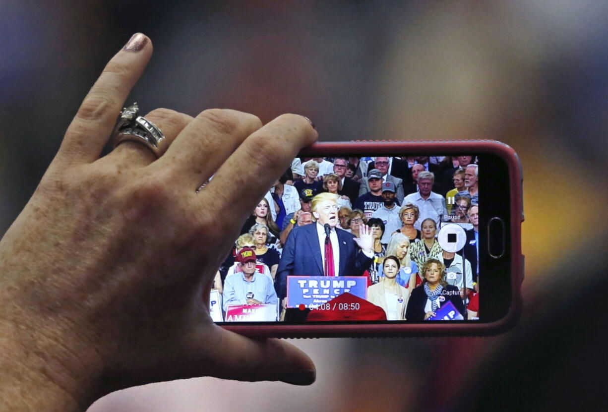 A person records as Republican presidential candidate Donald Trump speaks at a campaign rally in Akron, Ohio, on Monday.