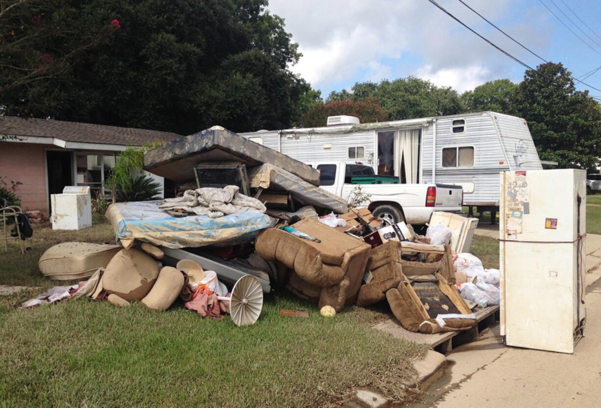 A growing pile of debris sits outside the flood-ravaged home of Carolyn and James Smith in Denham Springs, La., on Wednesday. Smith says she and four other adults will live for the time being in the travel trailer that one of her sons towed to the driveway after weekend flooding inundated the area.