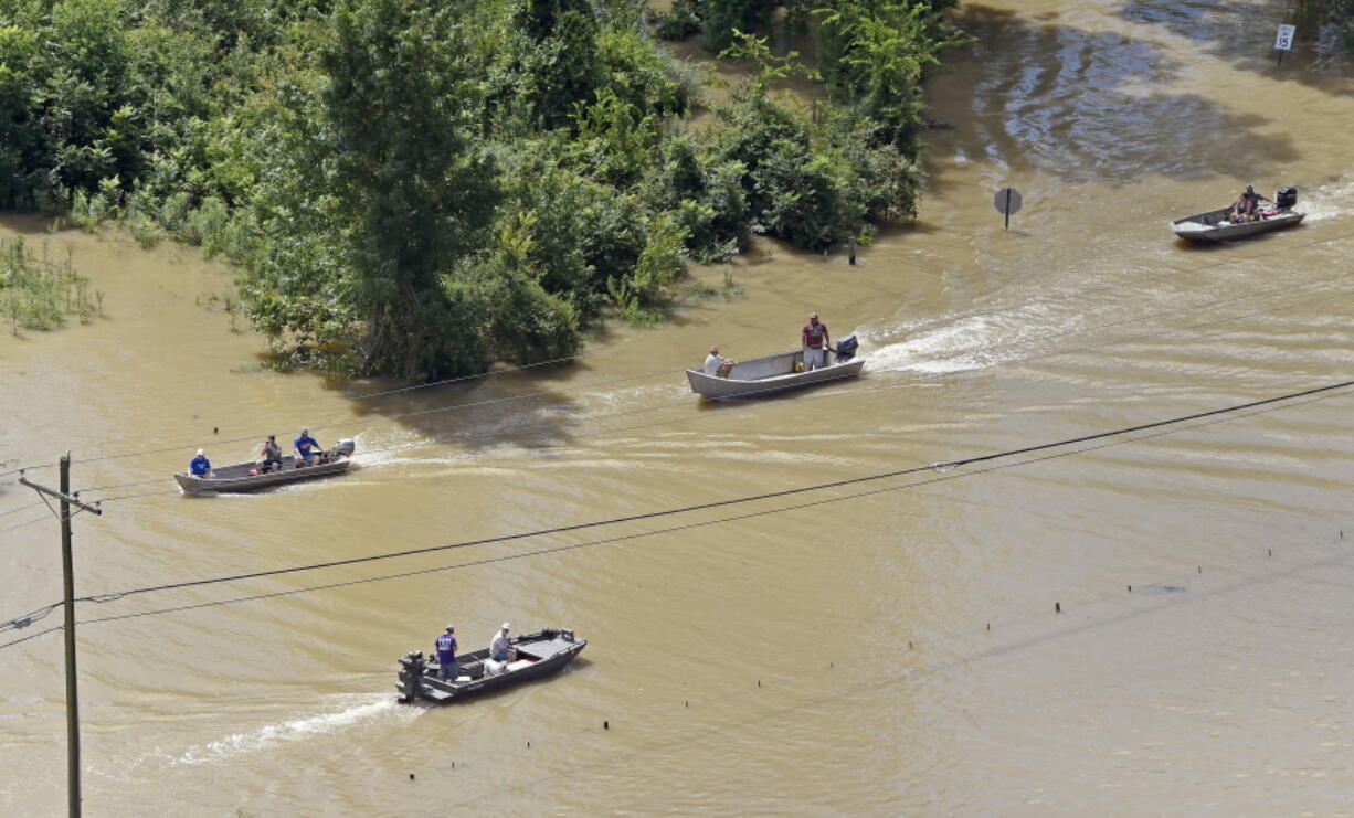 Boats travel Tuesday along Highway 431, flooded after heavy rains, in the Ascension Parish area south of Baton Rouge, La.