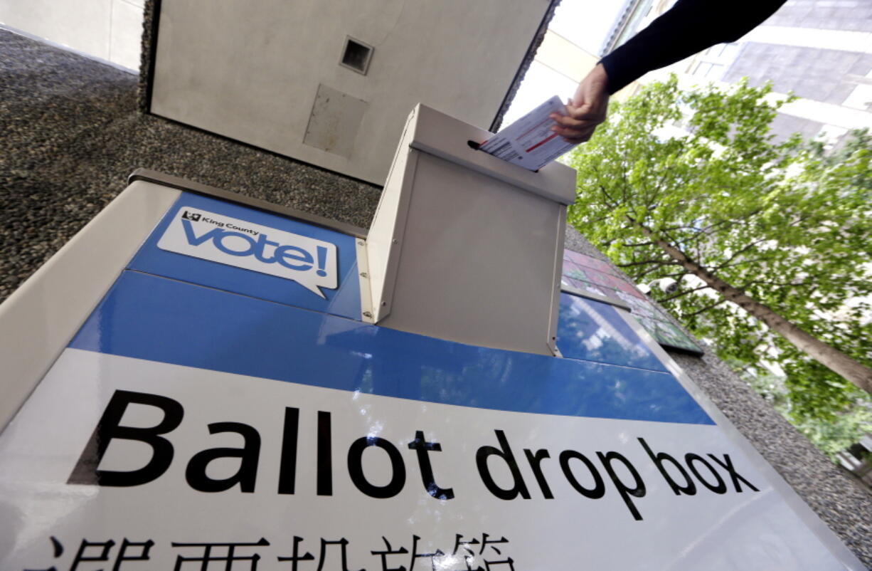 A voter drops a ballot into a ballot drop box Tuesday in Seattle. Washington&#039;s voters are weighing in on dozens of races across the state as they winnow their choices for offices ranging from Congress to the Legislature in the state&#039;s primary election.