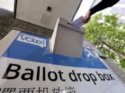 A voter drops a ballot into a ballot drop box Tuesday in Seattle. Washington&#039;s voters are weighing in on dozens of races across the state as they winnow their choices for offices ranging from Congress to the Legislature in the state&#039;s primary election.