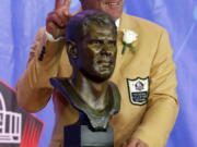 Former NFL quarterback Brett Favre poses with a bust of himself during an induction ceremony at the Pro Football Hall of Fame on Saturday, Aug. 6, 2016, in Canton, Ohio.