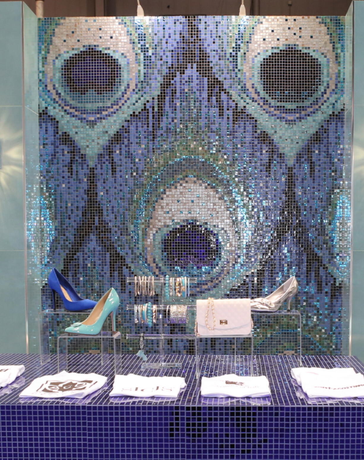 An installation designed by Capra at McCormick Place in Chicago during the 2016 Coverings trade fair, where international ceramic tile and stone flooring manufacturers displayed their wares. The installation, which showcased the creative use of mosaic tiles, features a stunning iridescent peacock feather, background.