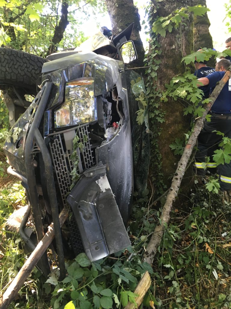 Crews work to free a driver from a pickup that went off eastbound state Highway 14 west of Camas on Saturday and ended up wedged in trees on a steep embankment.