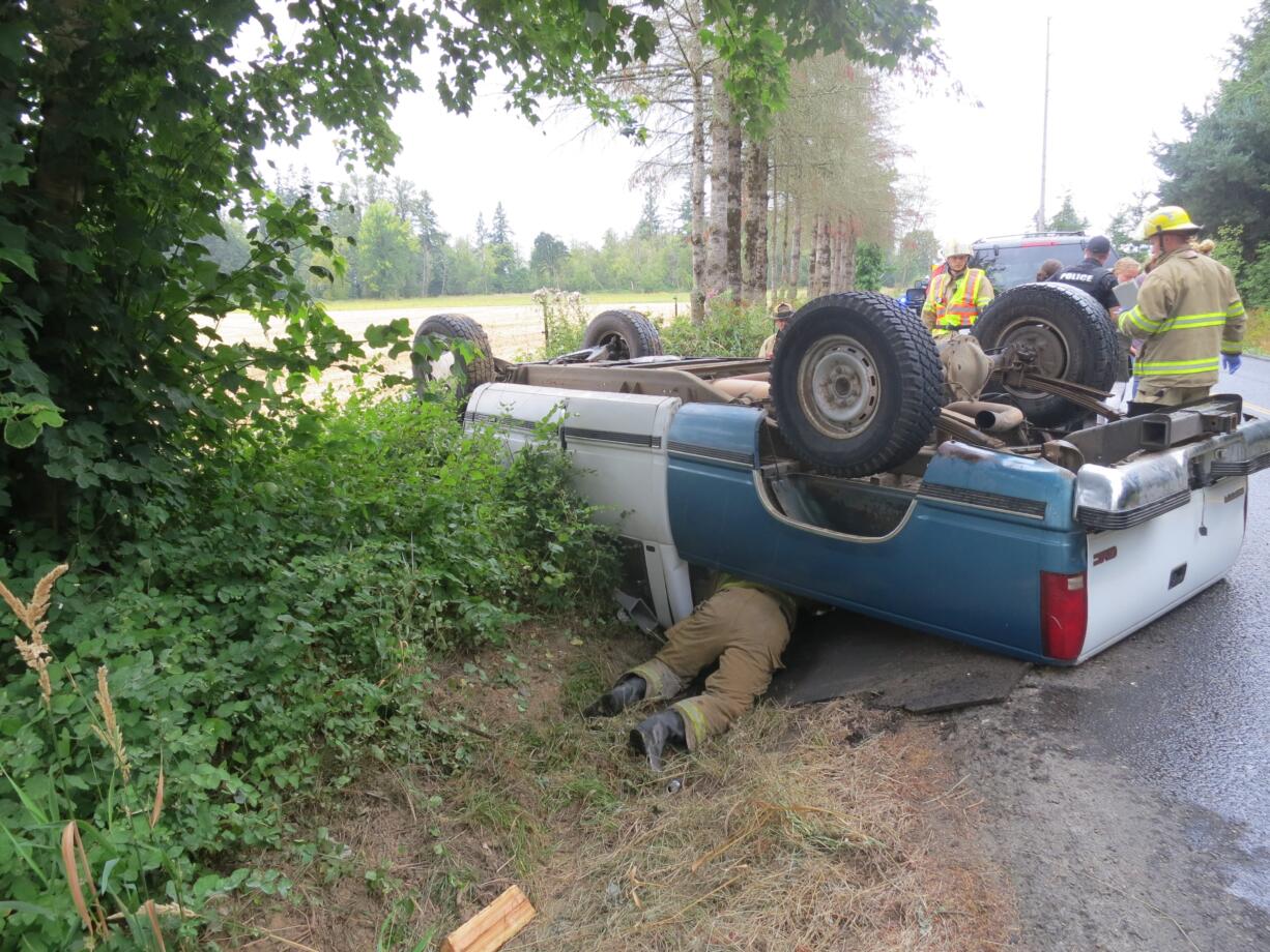 A firefighter crawls under a truck after it rolled near Daybreak school in Battle Ground on Monday morning.