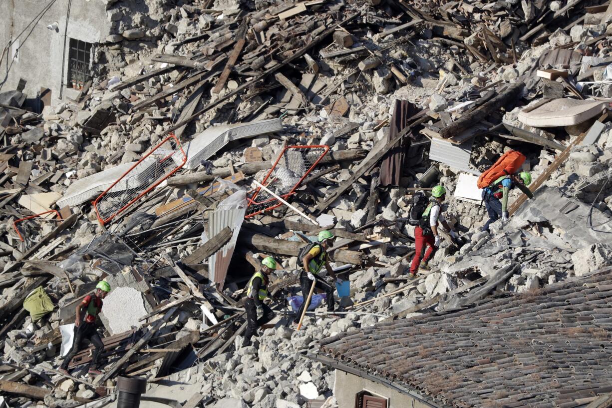 Rescuers make their way through destroyed houses following an earthquake in Pescara Del Tronto, central Italy, Thursday, Aug. 25, 2016. The magnitude 6 quake struck Wednesday at 3:36 a.m. (0136 GMT) and was felt across a broad swath of central Italy, including Rome where residents of the capital felt a long swaying followed by aftershocks.