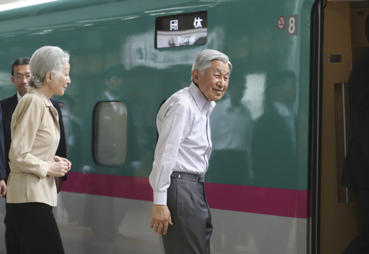 Japanese Emperor Akihito, accompanied by Empress Michiko, smiles as he gets on a Shinkansen or bullet train at Tokyo Station in Tokyo for their departure for the imperial villa in Nasu, northern Japan,  July 25.