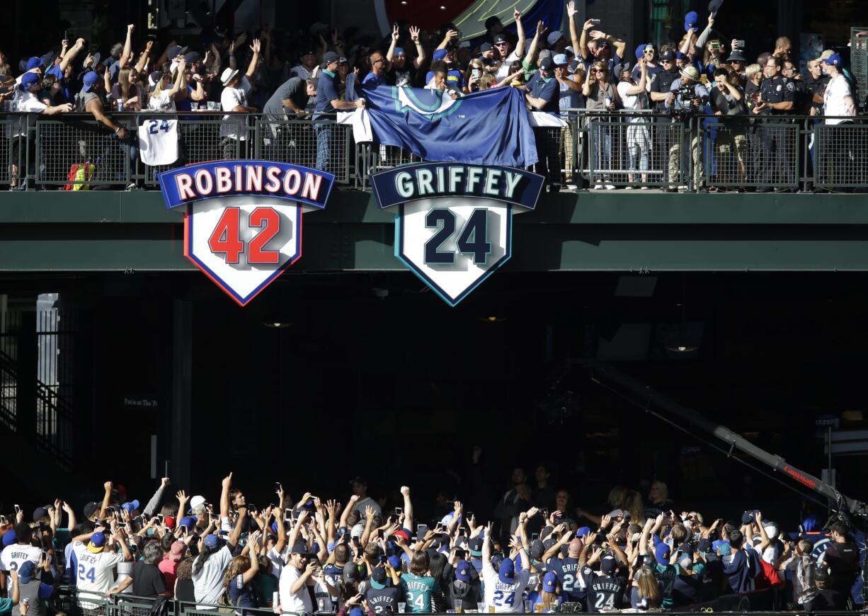 Taryn Griffey, center above number 24, the daughter of Seattle Mariners Hall-of-Famer Ken Griffey Jr., helps unveil Griffey's retired number 24 during a ceremony, Saturday, Aug. 6, 2016, at Safeco Field in Seattle. The number will be displayed next to Jackie Robinson's number 42 at Safeco Field. (AP Photo/Ted S.