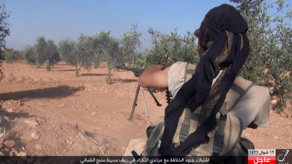 An Islamic State fighter fires his weapon during clashes with the Kurdish-led Syria Democratic Forces in Manbij, in Aleppo province, Syria.