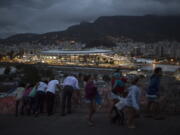 People walk on a viaduct at the Mangueira slum as the Maracana stadium is lit before the closing ceremony of the Summer Olympics in Rio de Janeiro, Brazil, Sunday, Aug. 21, 2016.