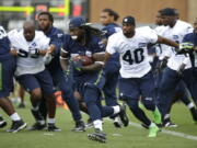 Seattle Seahawks running back Alex Collins, center eft, carries the ball during NFL football training camp, Saturday, Aug. 6, 2016, in Renton, Wash. (AP Photo/Ted S.