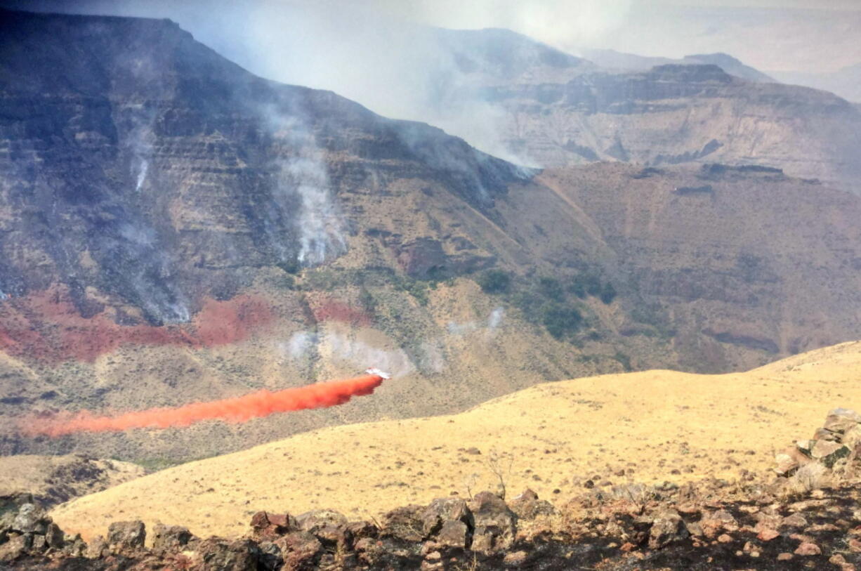 A plane drops fire retardant near the northwest side of Owyhee Canyon south of Vale, Ore., Wednesday, Aug. 24, 2016. The nearly 50-square-mile fire in eastern Oregon near the Idaho state line is now threatening Succor Creek State Park.