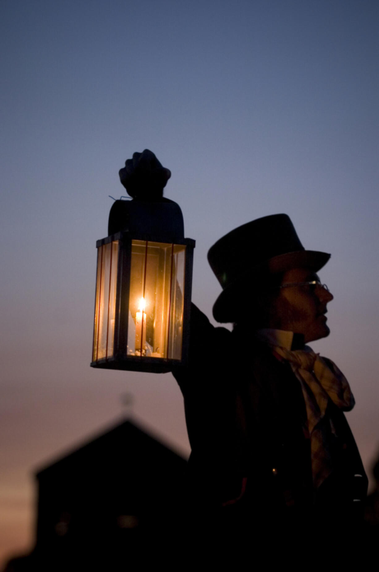 A re-enactor raises a lantern during an evening tour at Fort Vancouver National Historic Site.