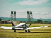 A plane sits at Pearson Field with the Interstate 5 Bridge in the background.