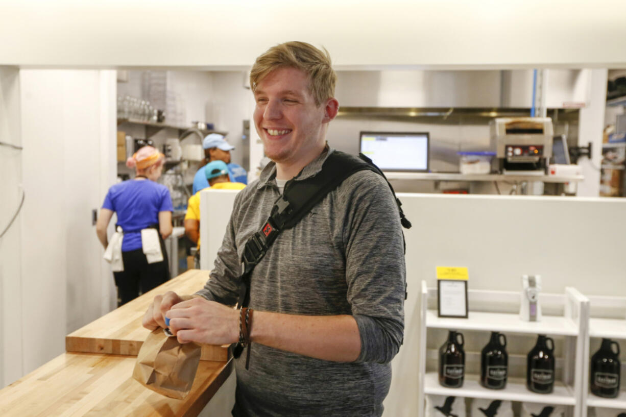 Dylan Dowd, 24, walks with his breakfast sandwich after he used an app to place the order seen here  at Eastman Egg at Ogilvie Transportation Center on Sept. 12, 2016 in Chicago. (Jose M.