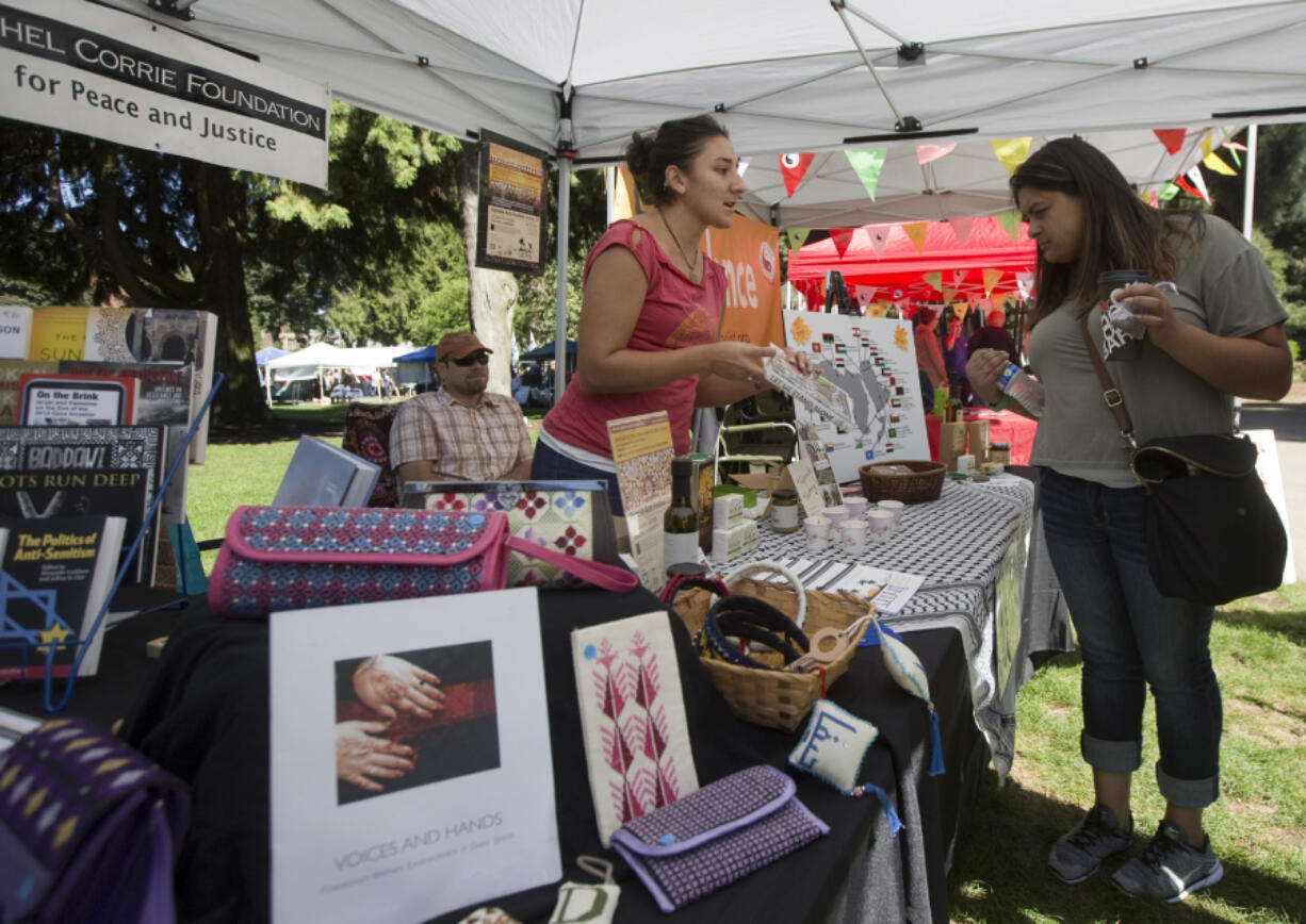 Jessica Babcock recommends a book about Palestine at the Rachel Corrie Foundation booth Saturday at the 13th annual Peace and Justice Fair in Esther Short Park in downtown Vancouver.